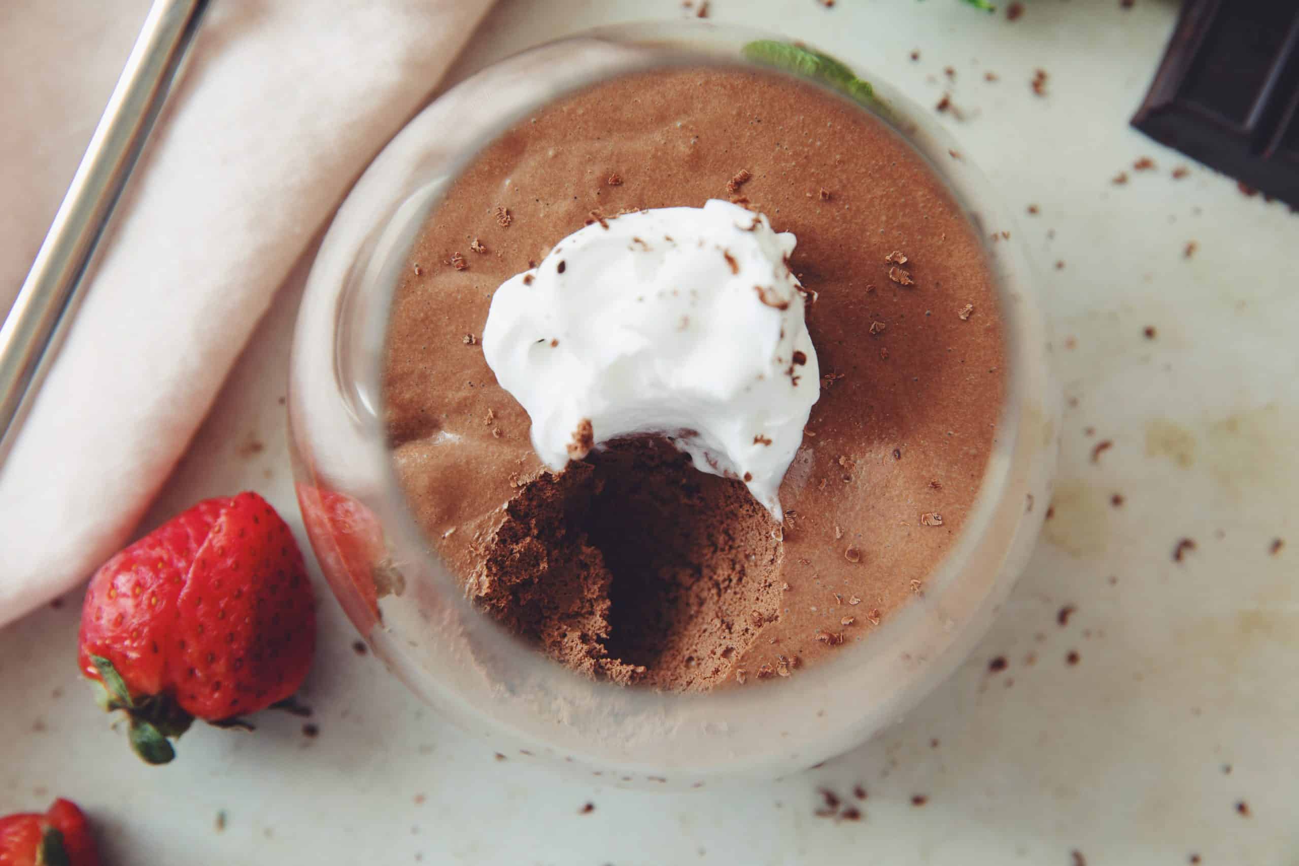 overhead of a serving of vegan chocolate mousse showing the texture with a spoon scoop taken out